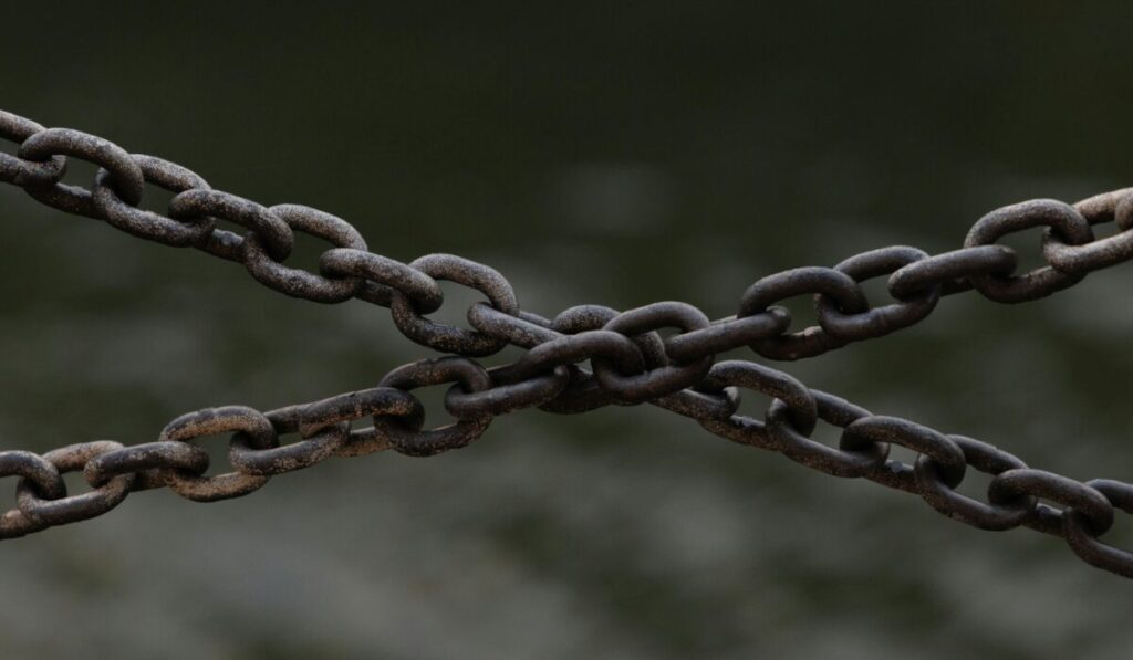 Close-up of crossed rusty chains over a blurred green background. — Photo by Ellie Burgin on Pexels