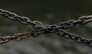 Close-up of crossed rusty chains over a blurred green background. — Photo by Ellie Burgin on Pexels