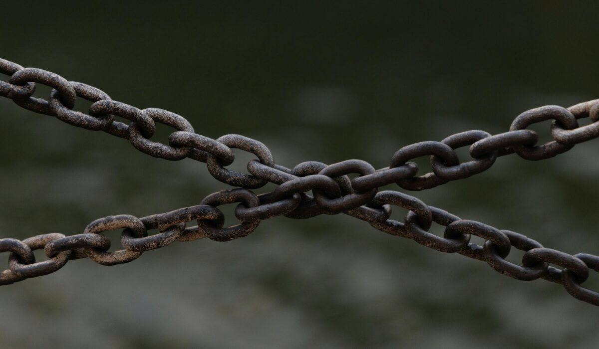 Close-up of crossed rusty chains over a blurred green background. — Photo by Ellie Burgin on Pexels